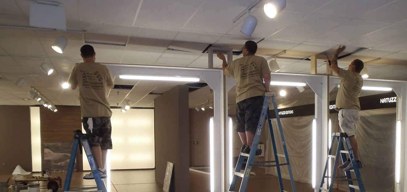 Thomas Carpentry & Construction crew on ladders installing floating wall built ins.